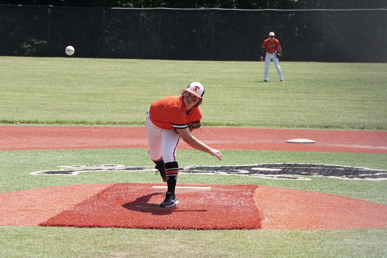 Young baseball pitcher throwing a pitch during a game on an outdoor field.