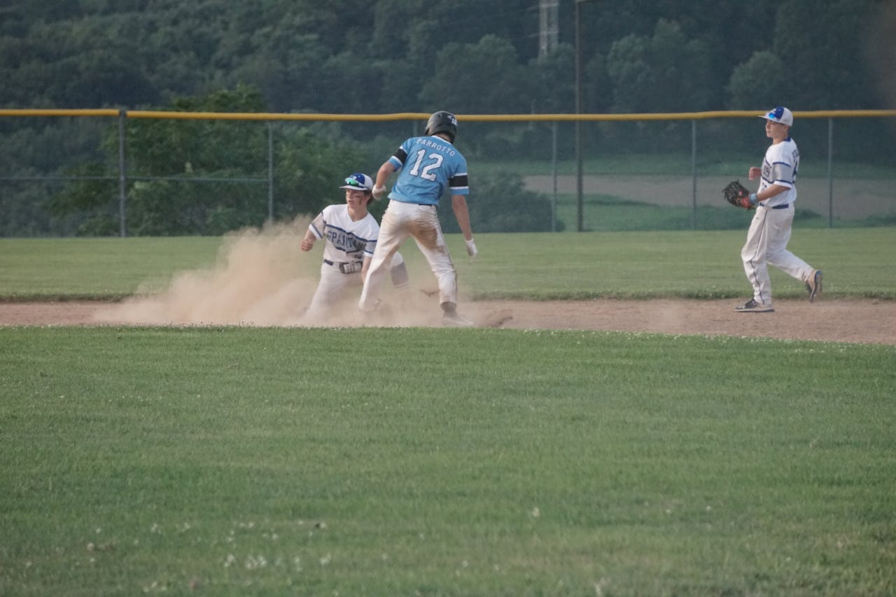 Exciting moment captured at a youth baseball game with players sliding on the dusty field.